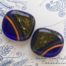 Load image into Gallery viewer, A pair of blue fused-glass cufflinks with orange stripes and brass triangles.
